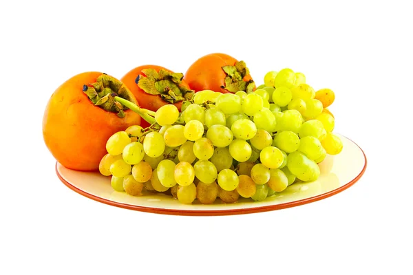 Winogrona i persimmons na płytkę. na białym tle — Zdjęcie stockowe