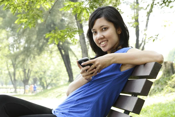Mulher com celular no parque — Fotografia de Stock