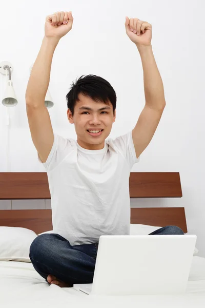 ラップトップはベッドと腕を上げる上で若いアジア人 — ストック写真