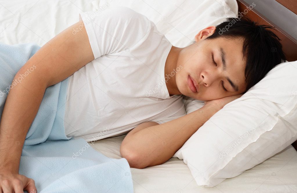 An Asian man sleeping on a bed