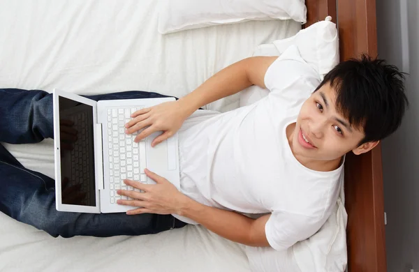 Asiatisk Man Arbetar Med Sin Laptop Sängen — Stockfoto