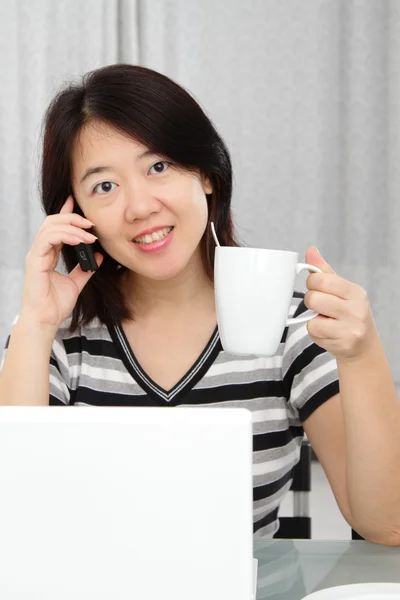 拿一杯咖啡工作时一个亚洲女人 — 图库照片