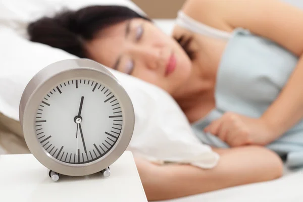 表时钟和一个女人睡在背景 — 图库照片