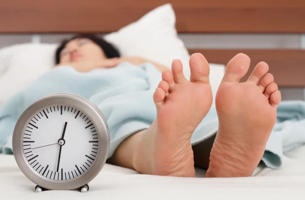 Ένα Ρολόι Και Πόδια Του Μια Κοιμισμένη Γυναίκα — Φωτογραφία Αρχείου