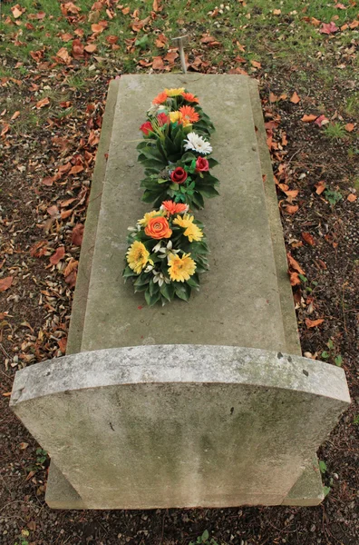 Tombstone täckt med blommor — Stockfoto