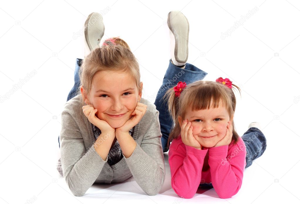 Two young sisters posing together in a studio