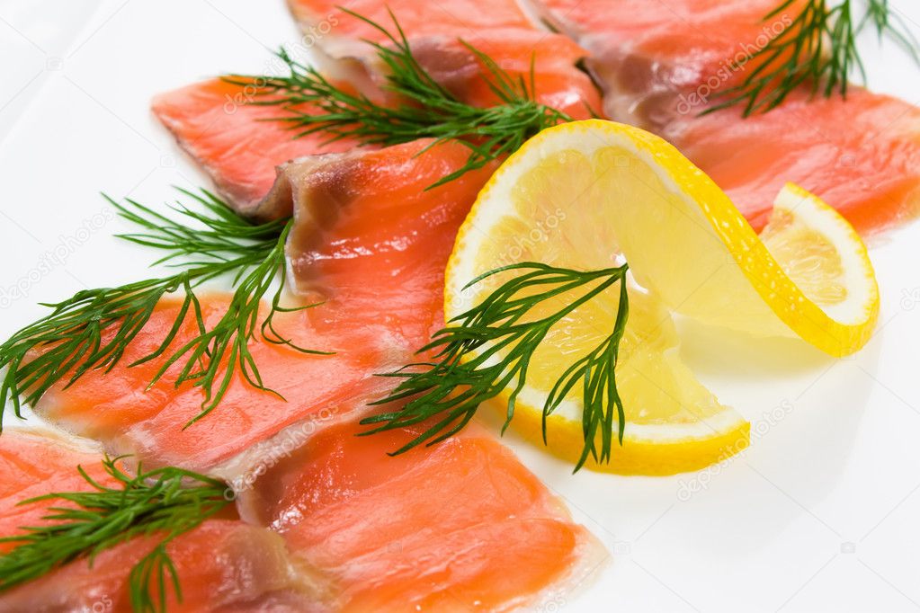 Slices smoked salmon with lemon and dill on a white plate
