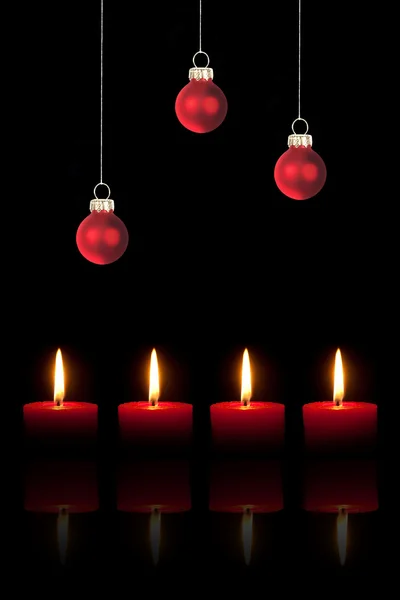 Tre röda julgran bollar och fyra röda ljus — Stockfoto