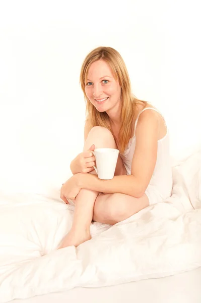 Giovane donna in camicia da notte bere caffè a letto — Foto Stock