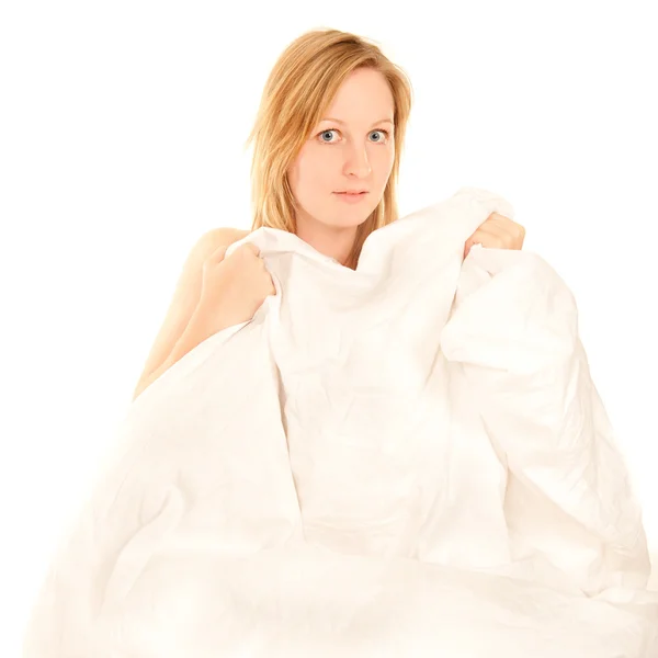 Naken ung kvinna gömmer sig bakom sängkläder — Stockfoto