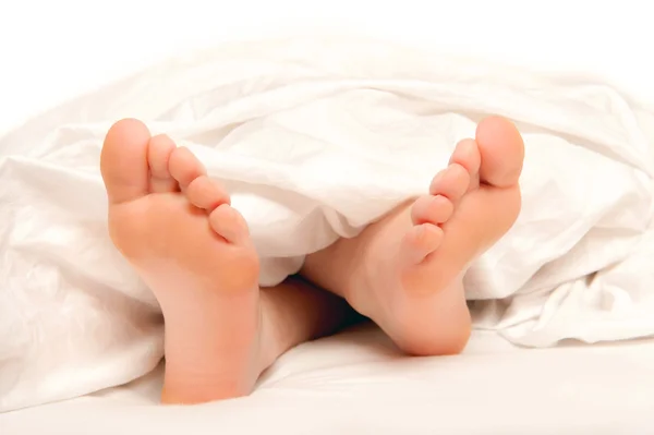 Bei piedi di una giovane donna sdraiata a letto — Foto Stock