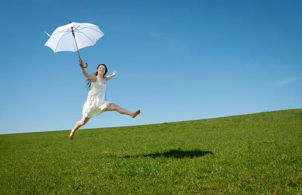 Красивая молодая женщина прыгает с белым зонтиком — стоковое фото