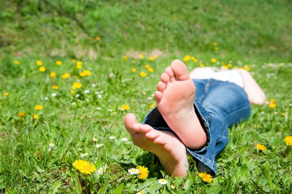牧草地で横になっている若い女性の足 — ストック写真