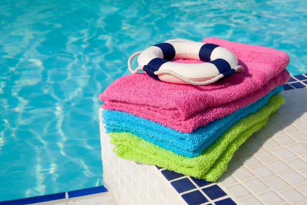 Colorful towels and life buoy near the swim pool — Stock Photo, Image