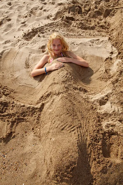Девушка похоронена под песком — стоковое фото