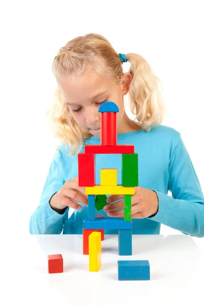 Menina loira jovem está jogando com blocos de madeira coloridos — Fotografia de Stock