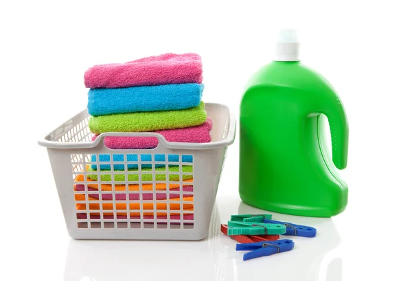 Cesta de lavandaria cheia de toalhas coloridas dobradas, cavilhas e bott — Fotografia de Stock