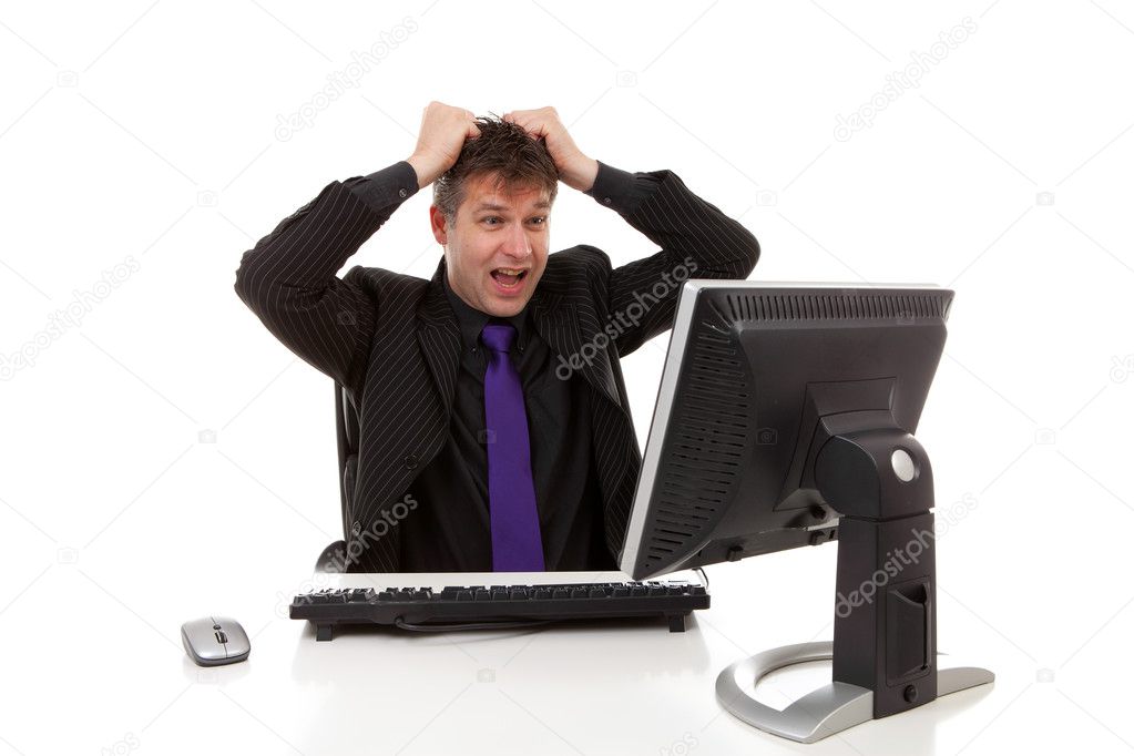 Businessman sitting behind desk is in despair, pulling his hair