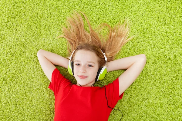 Girl is listening to music with headphones on — Stock Photo, Image