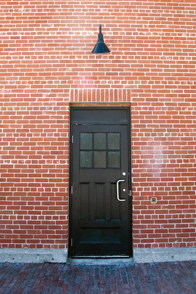 Puerta negra en la pared de ladrillo — Foto de Stock
