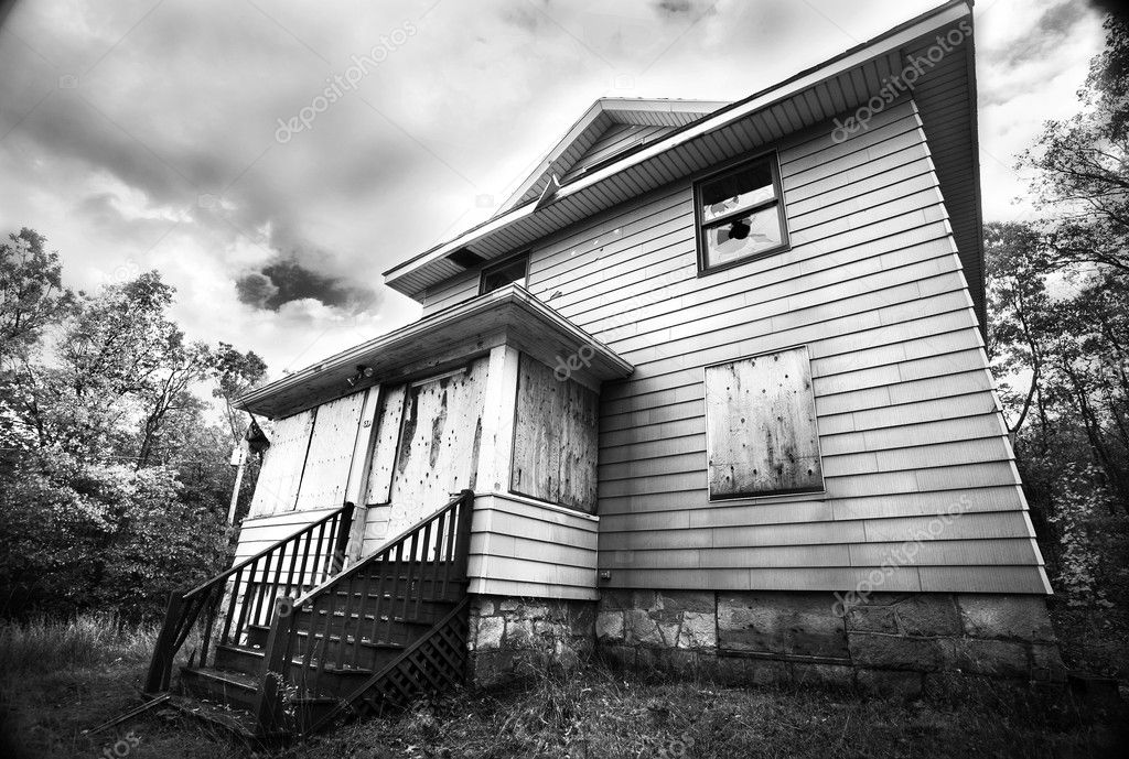 A boarded up, broken down, abandoned, haunted house in black and white.