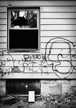 A run down abandoned house with broken window and graffiti. clipart