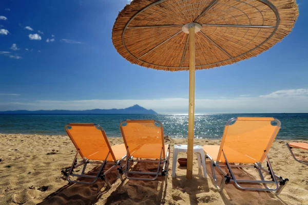 Decks and umbrella on beach — Stock Photo, Image