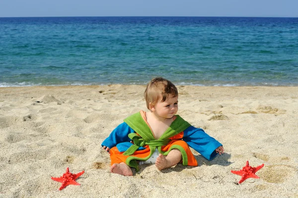 Baby girl playing with red sea stars on the beach — Stock Photo, Image