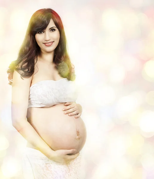 Усміхнена вагітна жінка дивиться на камеру. фон Боке — стокове фото