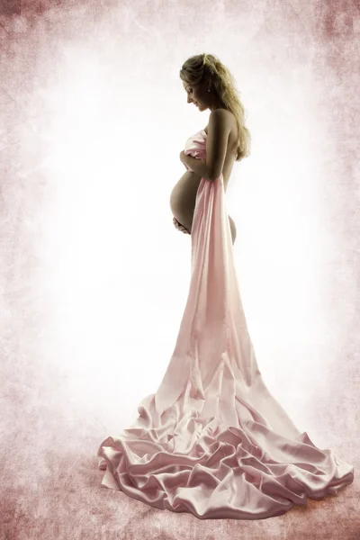 妊娠中の女性が腹を見てします。グランジ背景 — ストック写真