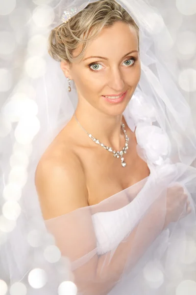 Bruden i vit slöja leende och tittar på kameran. — Stockfoto