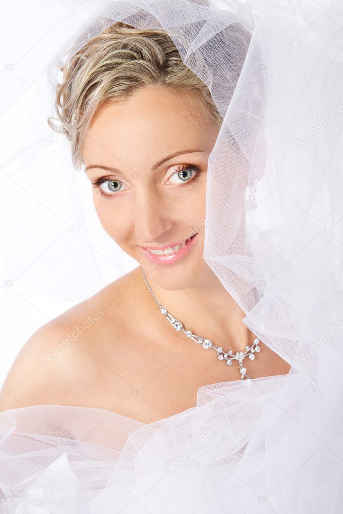 Bride in white veil smiling and looking at camera.