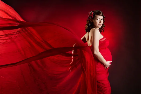 Έγκυος γυναίκα με κόκκινο χρώμα, κουνώντας φόρεμα — Φωτογραφία Αρχείου
