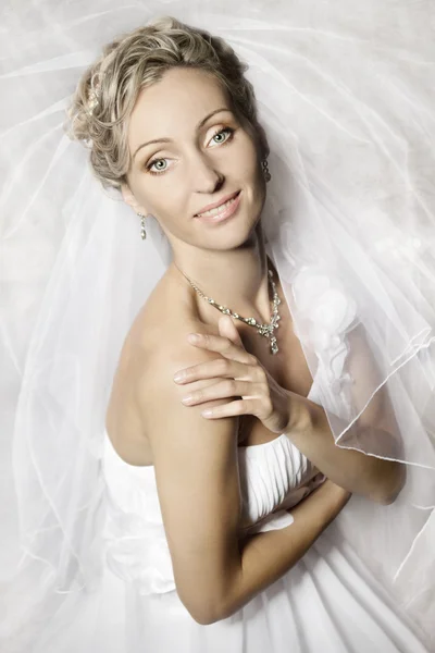 Braut in weißem Schleier blickt und lächelt in die Kamera — Stockfoto