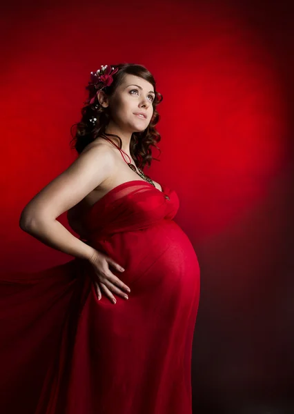 Těhotná žena v červené šifónové šaty. — Stock fotografie