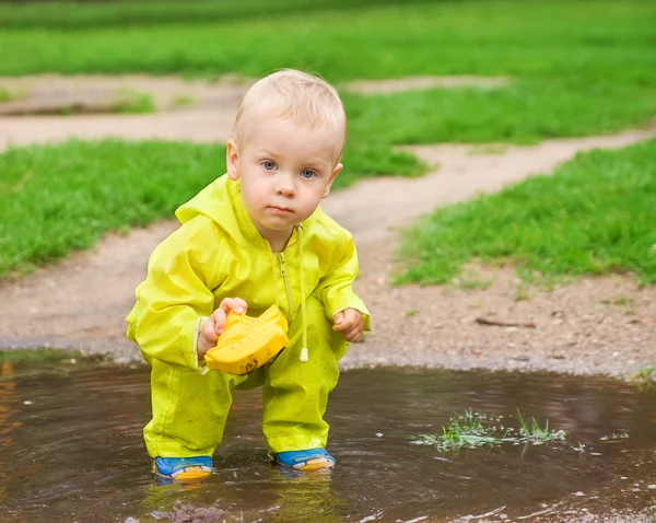 Child playing with ship in the puddle outdoor — Stock Photo, Image