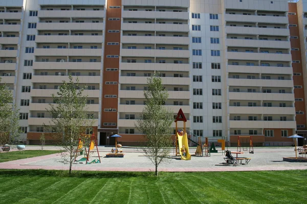 子供たちは 緑の草のための遊び場の新しいアパートのブロック — ストック写真