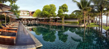 A panoramic image of a hotel infinity pool in Thailand with hotel in the background. clipart