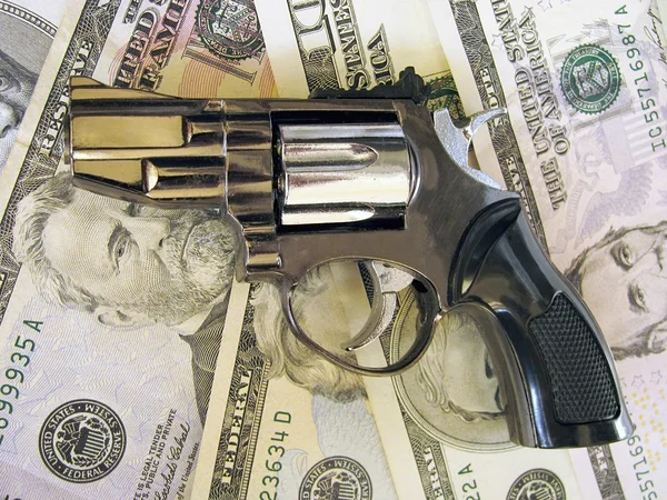 stock image Gun lying on cash (heap of dollars banknotes)