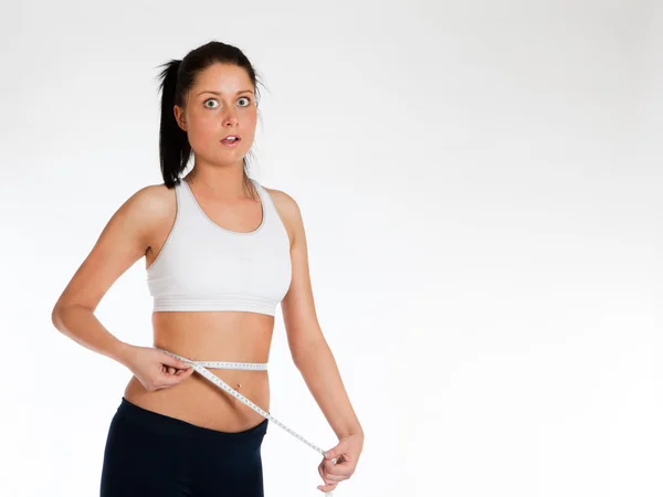 Foto de Mujer midiendose la cintura con un metro sobre un fondo