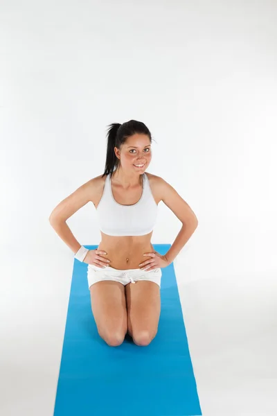 Mujer haciendo ejercicio sobre alfombra de yoga azul Imagen De Stock