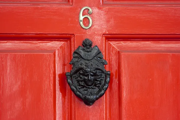 Красная деревянная дверь с большим грузинским дверным молотком Стоковое Фото