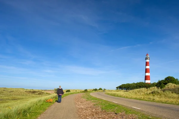 Man is walking in landscape with lighthouse — Stock Photo, Image