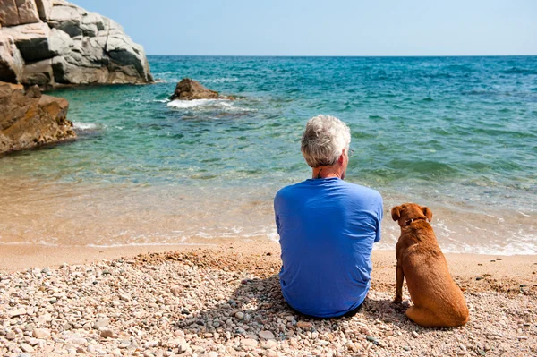 Чоловік зі своїм собакою на пляжі — стокове фото