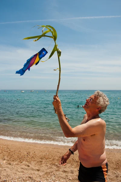 Elderly man is playing at the beach — Stock Photo, Image
