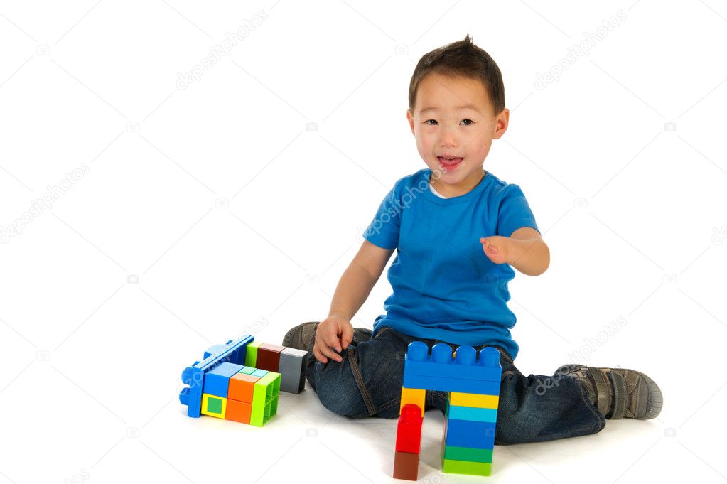 Little Chinese boy with small handicap is playing with wooden crane an blocs