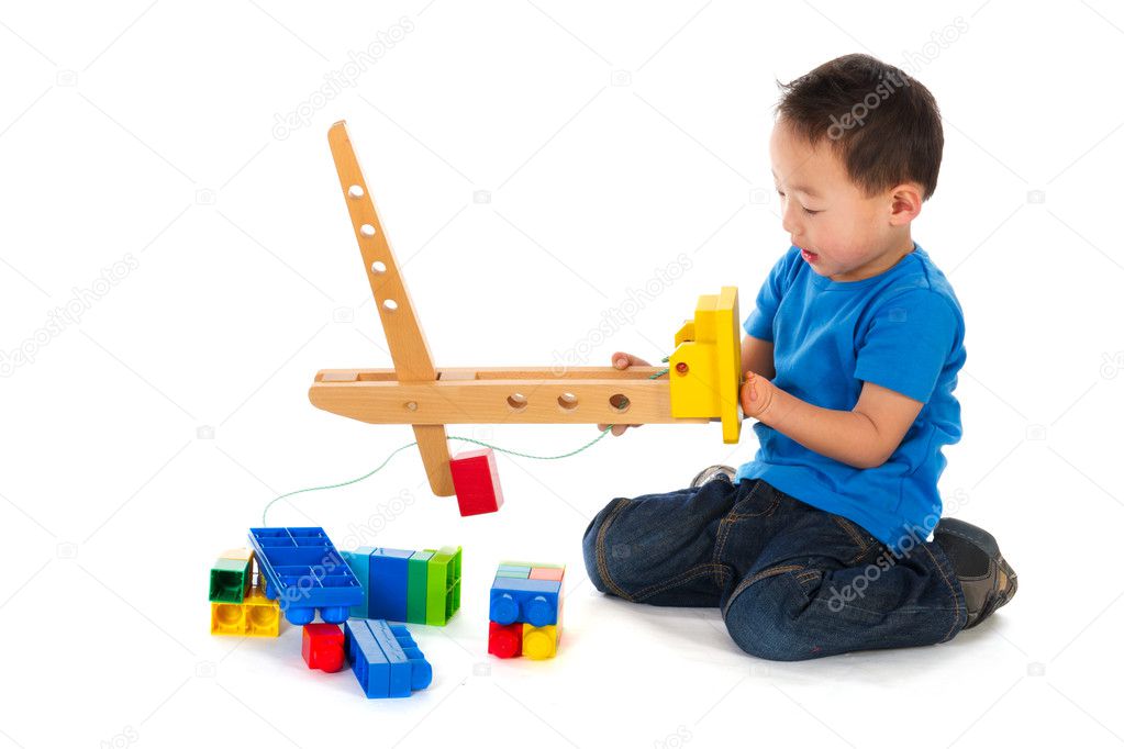 Little Chinese boys playing with wooden crane an blocs