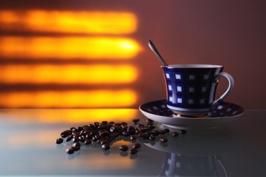 Cup and coffee beans on a glass table. clipart