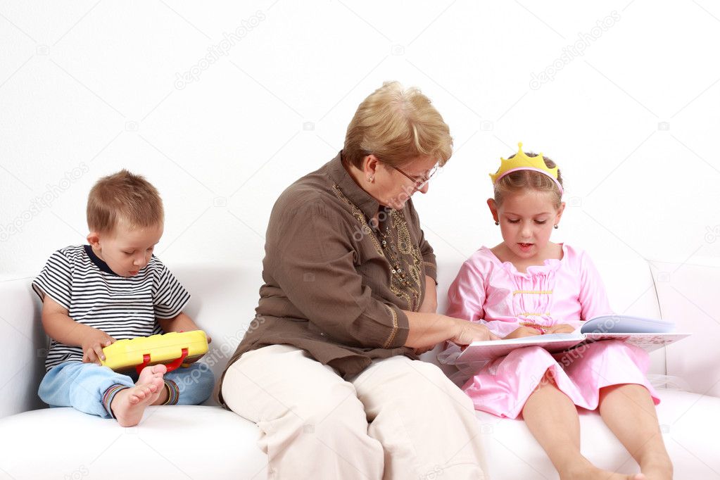 Grandma helping gorl by reading and playing with baby