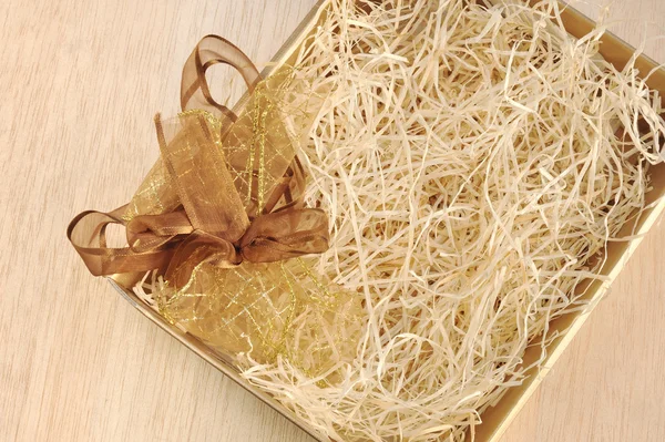 Open gift box and bow - filled with packing bast — Stock Photo, Image